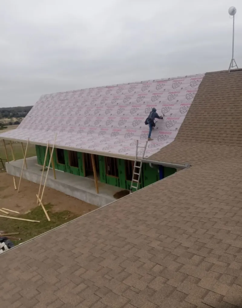 Worker preparing underlayment for a metal roof installation in Findlay